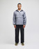 A packable anorak jacket in grey, featuring a half-zip closure and a logo, displayed by a model wearing black pants.