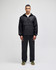 A black packable anorak jacket worn by a model, paired with dark trousers and shoes, featuring a logo.