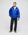 A packable anorak jacket in vibrant blue, featuring a hood and logo, worn by a model with black pants and sneakers.