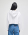A white cropped hoodie with a hood, displayed from the back, paired with blue jeans. It features a logo.