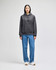 A grey cropped hoodie features a front pocket and a logo, paired with blue baggy jeans and white sneakers.