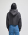 A black cropped hoodie with a hood, worn by a person facing away, paired with blue jeans.