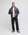 A model wearing a grey Champion Powerblend® full-zip hooded sweatshirt with a white shirt and black pants.