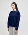 A woman wearing a navy blue Champion Powerblend® crewneck sweatshirt paired with grey bottoms, featuring a logo.