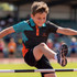 A boy jumps over a high jump bar while wearing a custom active polo in black, teal, and orange with a logo.