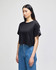 A cropped black t-shirt with short sleeves and a logo detail, styled with blue denim jeans.