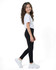 A pair of black kids' leggings worn by a girl wearing a white t-shirt and white sneakers, showcasing a side view.