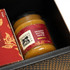 A jar of brandy butter sauce in a black box, featuring a decorative label and a logo. The sauce is golden in colour.