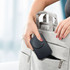 A black foldable 3-in-1 magnetic wireless charger being placed into a grey bag with dual handles.