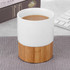 A ceramic mug with a white upper section and a natural bamboo base, filled with a warm beverage.