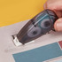 A hand using a transparent, grey Metz Glue Tape dispenser on paper, displaying a smooth adhesive application.