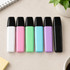 A set of highlighters in white, pink, green, blue, purple, and black, arranged neatly on a desk.