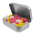 A silver tin containing a variety of jelly beans in pink, yellow, and white colours.
