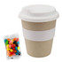 A bamboo cup in natural colour with a white lid, accompanied by a packet of colourful jelly beans.