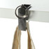 A silver mobile stand and hanger key ring clipped to a flat surface, holding a fabric strap.