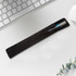 A black velvet pouch containing a pen, positioned on a desk with a keyboard and a plant.