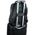 A black backpack with adjustable straps is secured on top of a rolling suitcase, featuring a small pocket on the side.