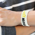 A large white silicone wristband with yellow and black text, featuring a logo.