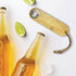 A drink bottle opener in bamboo with a metal bottle cap remover and a rope attachment, alongside two beer bottles.