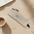 A small, beige cosmetic bag with a zip and a logo, placed on a wooden surface near a cup of coffee and an open notebook.