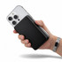 A power bank in black being held next to a smartphone, showcasing a sleek design and compact size.