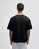 A black heavyweight cotton unisex boxy T-shirt displayed from the back, worn over grey shorts.
