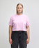 A pink heavyweight cotton women's garment dyed crop boxy t-shirt, paired with blue jeans, featuring a logo.