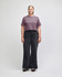 A heavyweight cotton women's crop boxy t-shirt in a muted purple, paired with blue jeans. The model stands against a plain background.