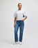A woman stands in a grey, mid-length boxy top paired with light blue wide-leg jeans, wearing white shoes.