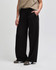 Wide leg pants in black, featuring a drawstring waist and side pockets, showcased from the side view.