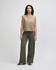 A model wearing a beige sleeveless top and olive green wide-leg pants, standing against a neutral background.