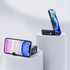 A mobile phone stand in black, holding a smartphone, displayed on white pedestals against a light background.