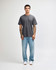 A grey unisex short sleeve t-shirt displayed on a model wearing light blue jeans and white shoes.