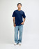 A navy blue unisex short sleeve T-shirt on a model, paired with light blue jeans. The shirt has a logo.