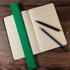 A green 30cm recycled plastic ruler next to a black marker and a blue pencil on a dotted notebook.