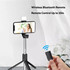 A black LED selfie stand with a smartphone mounted on it, featuring a wireless Bluetooth remote and extendable legs.