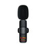 A black wireless microphone with a round top and a small logo, featuring a clip for attachment.