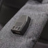 A grey backpack strap featuring a USB port. The fabric has a textured appearance.