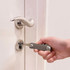 A silver multi-tool is being used to unlock a door, with a sleek door handle visible in the background.