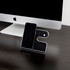 A sleek black and silver wireless charging stand for a phone and other devices, positioned next to a computer.