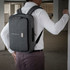 A grey laptop bag is worn on a person's back, featuring a sleek design and a front pocket.