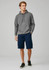 Men's dress shorts in navy, paired with a grey hoodie and black sneakers, displayed in a casual stance.