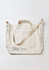 A cream tote bag with a strap, featuring a logo and patterned detailing along the edges.