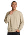 A man wearing a beige adult poly cotton fleece sloppy joe, featuring a casual design and crew neckline.
