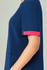 Unisex navy scrub top with pink accents on the sleeves, featuring a side pocket and a circular logo detail.