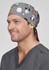 A unisex printed scrub cap in grey with various animal illustrations, featuring a tied back design.