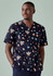 A men's scrub top featuring a navy background with colourful space-themed prints, including rockets and planets.