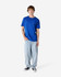 A blue heavyweight cotton unisex T-shirt is worn by a person paired with light blue jeans and black sneakers.