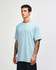 A light blue heavyweight cotton unisex t-shirt on a model, featuring a simple design and a logo.
