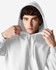A white Gildan Heavy Blend adult hooded sweatshirt is worn by a young man adjusting the hood. The product features a logo.